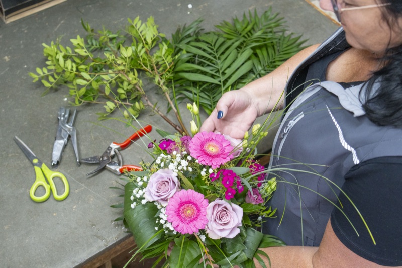 Floristin bindet von Hand einen bunten Blumenstrauß mit Gerbera und Rosen
