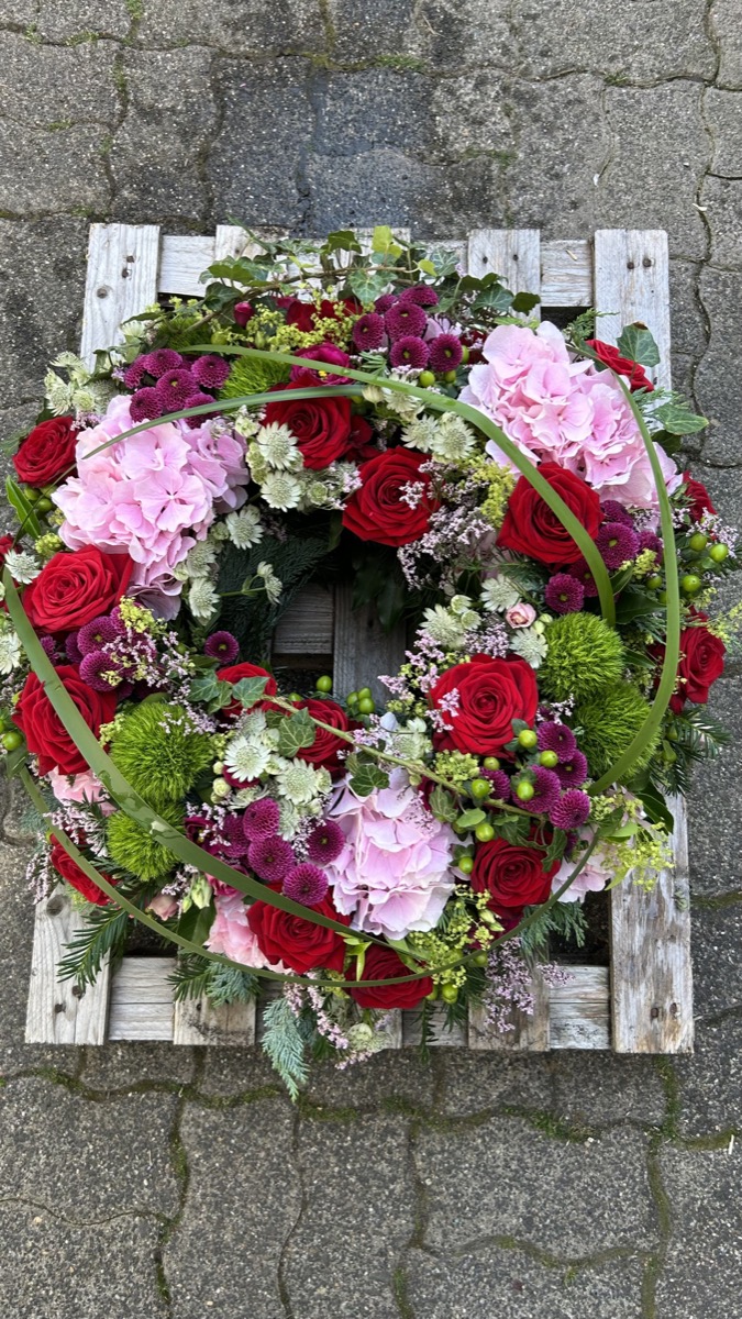 Trauerkranz mit roten Rosen und rosa Hortensien