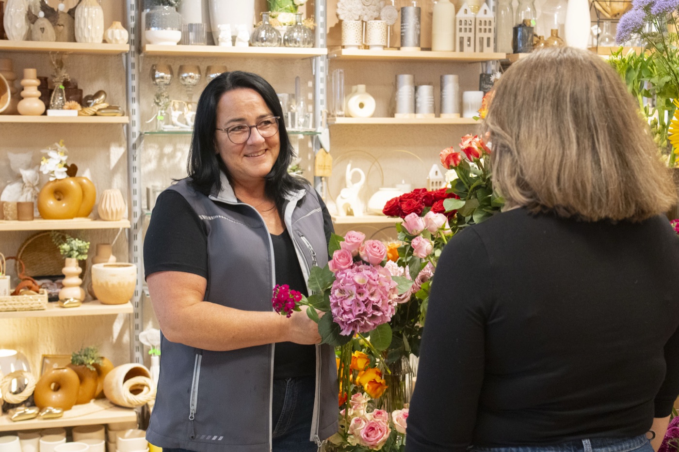 Übergabe eines Blumenstraußes an eine Kundin